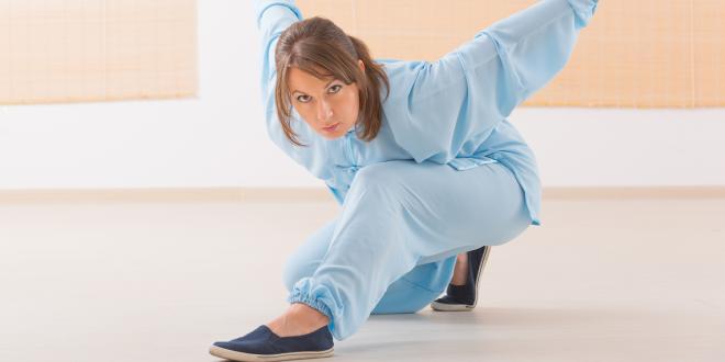 a woman practicing qi gong tai chi in a low position