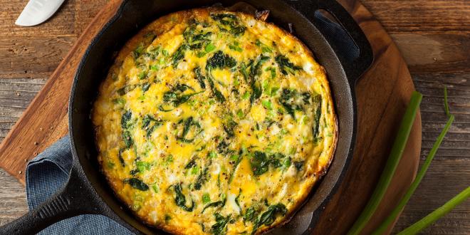 a spinach frittata in a pan with crumbled cheese