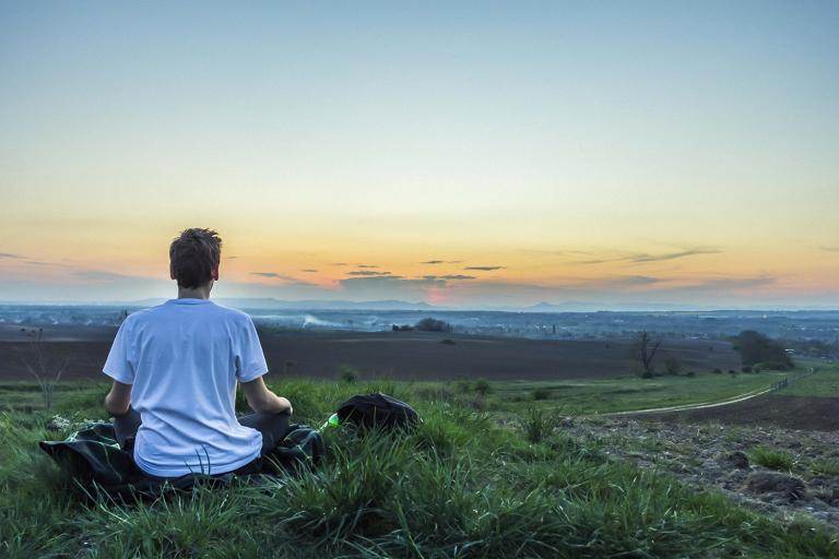 a man calmly watching the sun set over the water